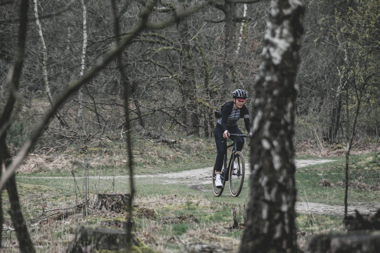 Ein Radfahrer mit Helm fährt mit einem Gravelbike auf einem Feldweg.